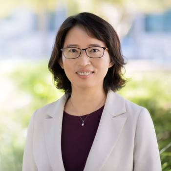 A photo of Chiung Yu. She is wearing glasses, a burgundy shirt with a light beige blazer over top. She is smiling and has chin length dark brown hair. 