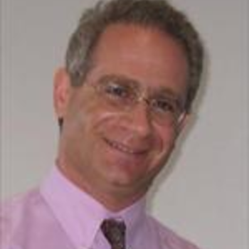 A photo of Jeffrey. He is smiling and wearing glasses, a pink collared shirt with a tie. He has short salt and pepper hair.