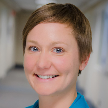 Erin is smiling at the camera for a professional headshot. She has short light brown hair brushed to the side and is wearing a light blue shirt. 