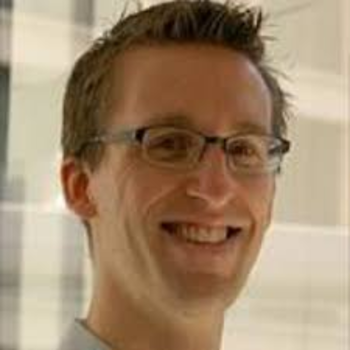 Thomas smiling - he is wearing glasses and has short light brown hair. 