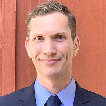 A professional headshot of Aaron