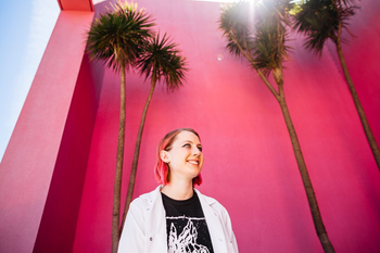 student standing in front of pink wall