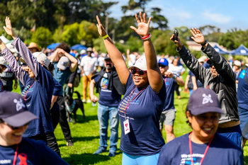 Group doing stretches outside with arms raised