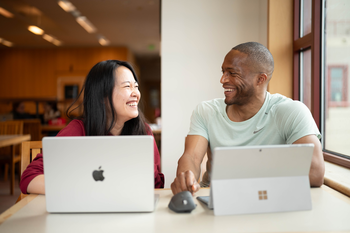 two people on computers smiling