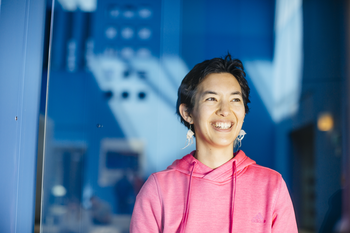 Woman smiling, standing in front of blue wall 
