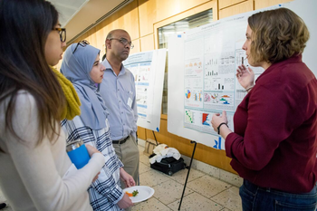 A woman presenting a scientific poster to three people